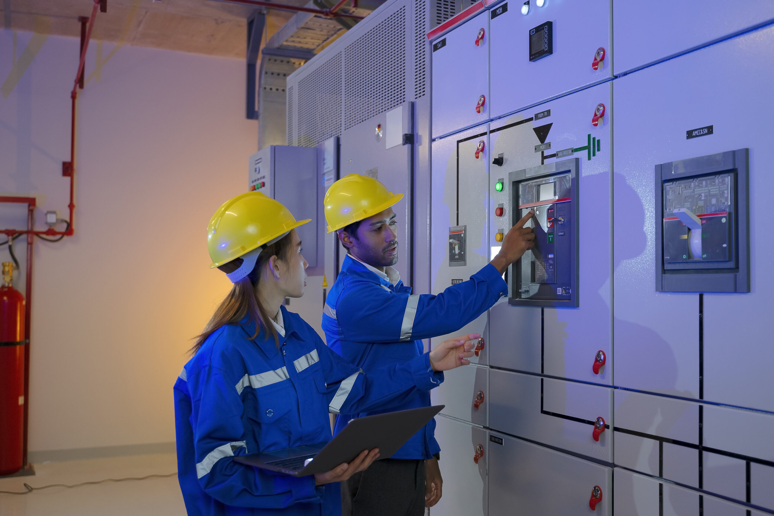Maintenance engineers are checking electronic system at basement building. Blue collar worker and engineer.